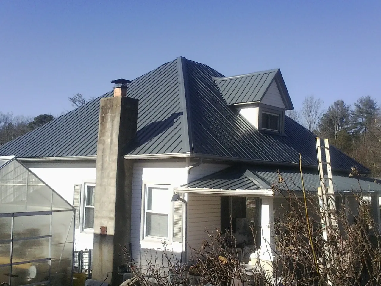 Dark blue standing seam metal roof on a white farmhouse with dormer — Slate & Tile Roof Repair by Roofing Brothers in Williamsburg