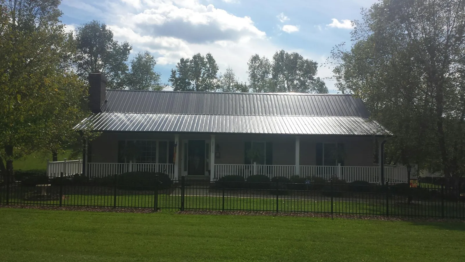 Gray metal roof on a brick ranch with a full width front porch — Gutter Guard Installation work by our crew in Williamsburg