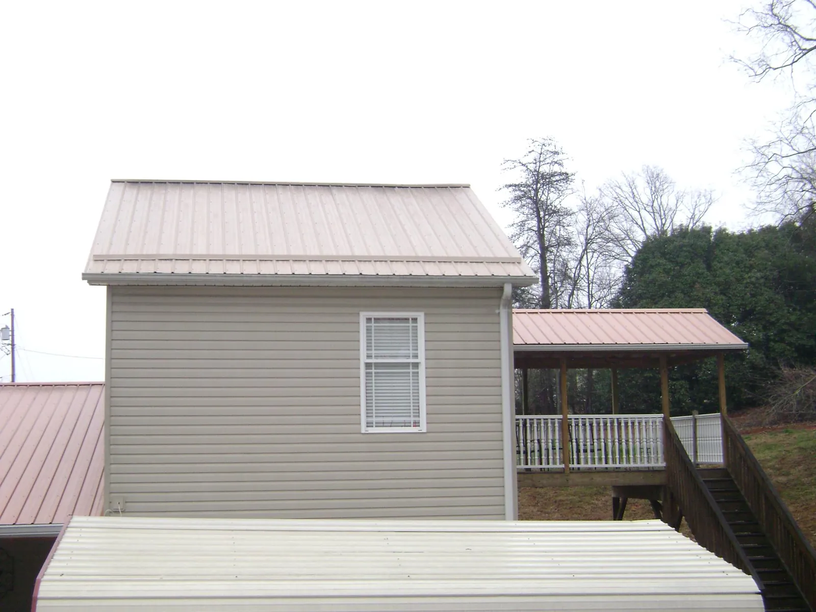 Tan metal roofs on a two story addition and attached porch, from a Roof Replacement job in Williamsburg